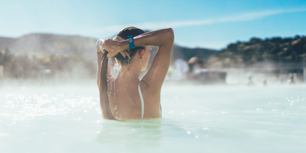 rear view of young woman relaxing in hot pool in Iceland